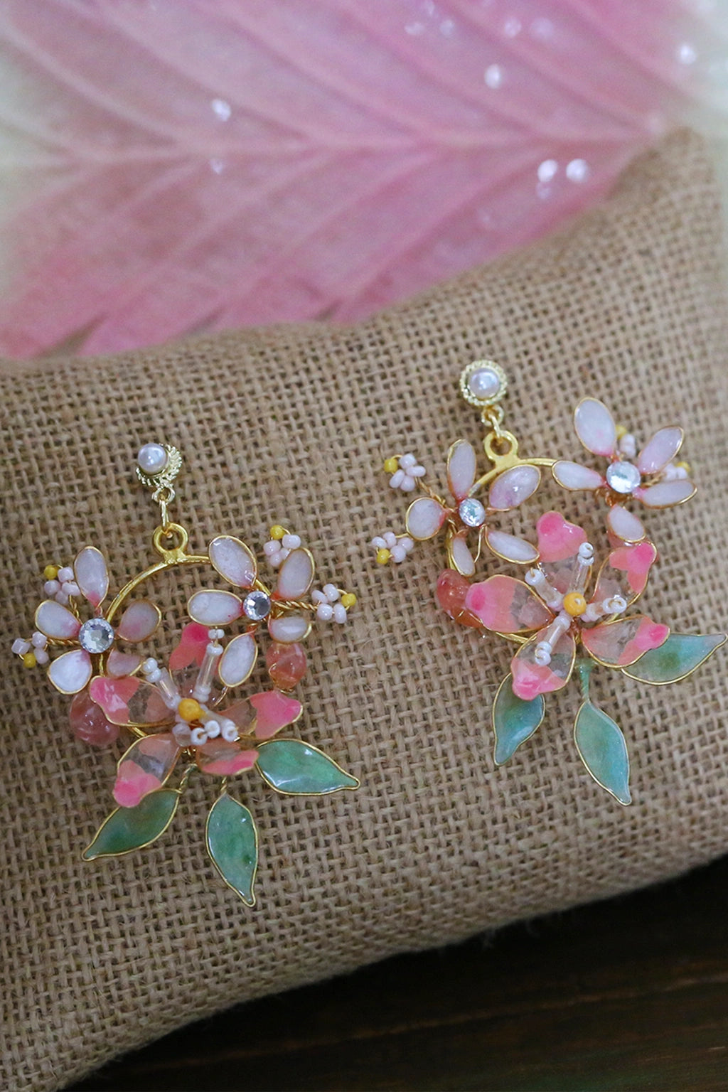 Handmade blush pink resin floral earrings with pearls and green leaves on burlap