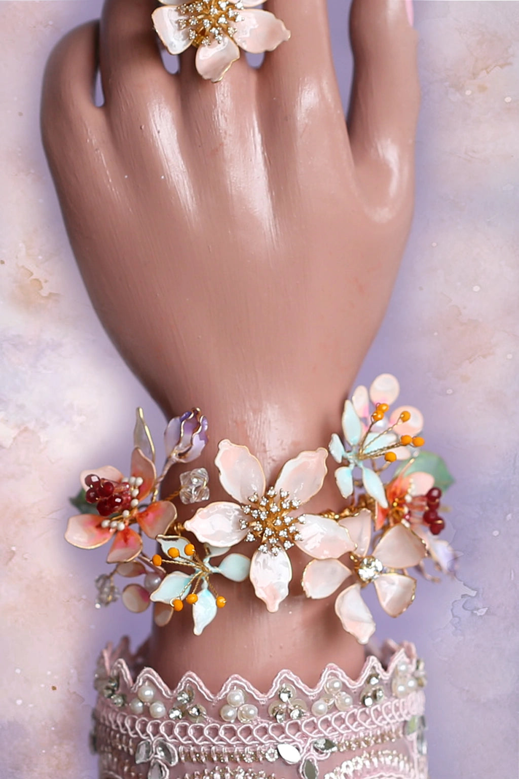 Hand displaying Handcrafted resin flower bridal bracelet with coral and pastel blooms. Lightweight, customizable & perfect for Haldi, Mehendi, weddings. Part of the Coral Caress Bridal Jewelry Set.