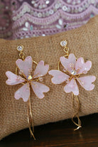 Handmade blush pink resin flower earrings made with gold plated wire and crystal accents displayed on a jute cushion, perfect for bridal wear and festive occasions.