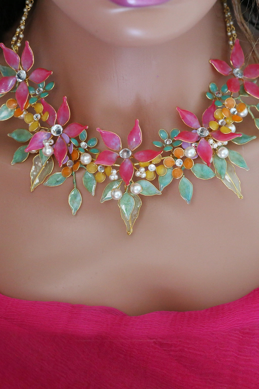 Mannequin wearing handmade resin flower bridal necklace featuring pink flowers with green and gold leaves — learn to create this necklace in the Rose Reverie resin jewelry class.