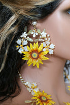 Close up of a woman wearing handcrafted resin sunflower earrings with yellow and orange petals, white flower accents, green resin leaves and pearls, perfect for bridal haldi or mehndi.