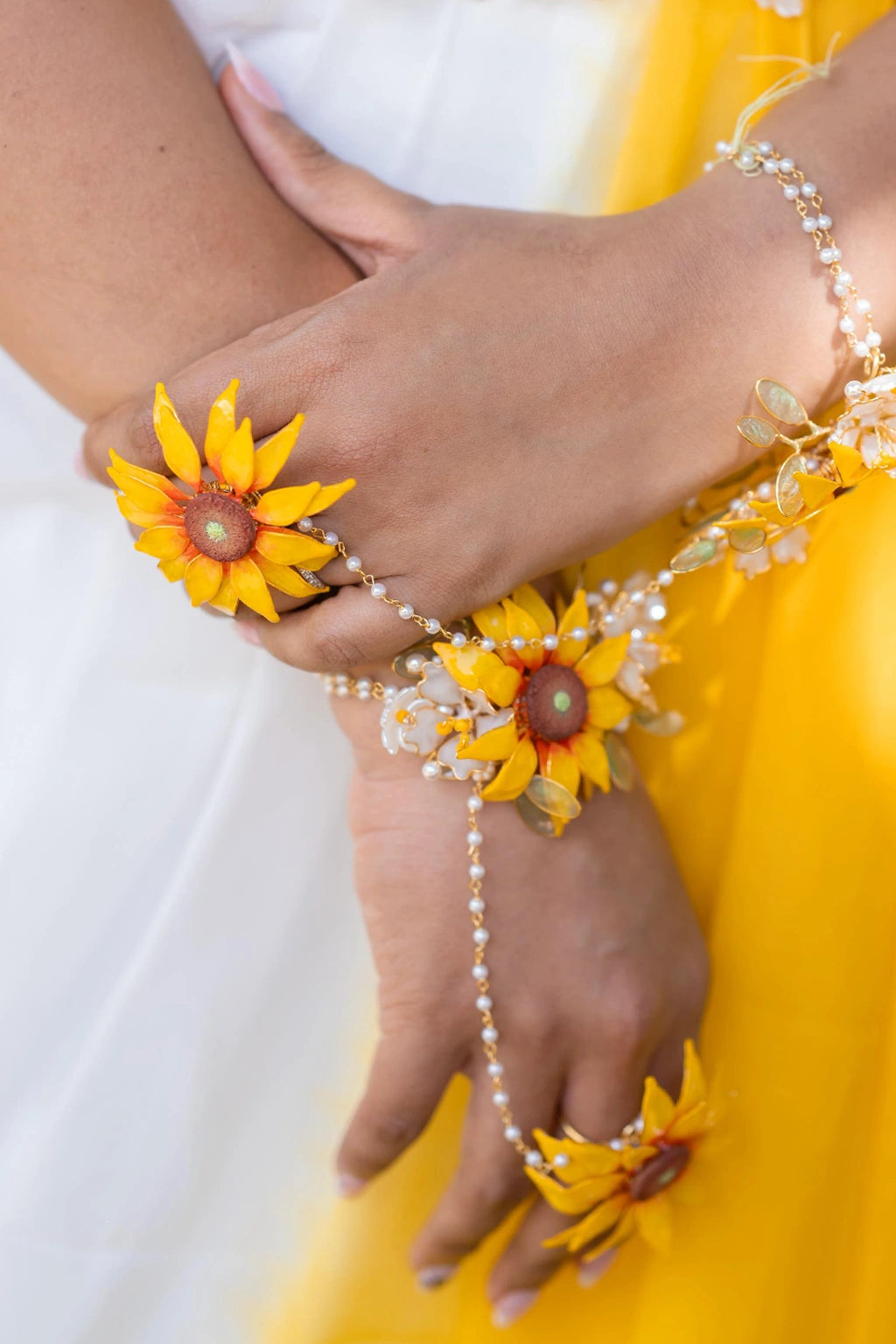 Close up of hand wearing Handmade resin sunflower haathphool – lightweight, customizable bridal hand jewelry for Haldi, Mehndi & wedding looks. Crafted with gold-plated wire, resin flowers & pearls.