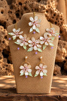 Blush pink resin flower bridal jewelry set with pearl bead necklace, earrings and maang tikka on a display stand