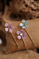 Three handmade resin flower bobby pins in pastel pink, aqua blue and lavender with rhinestone centres on gold-tone hair pins, by Seema Clay Jewelry